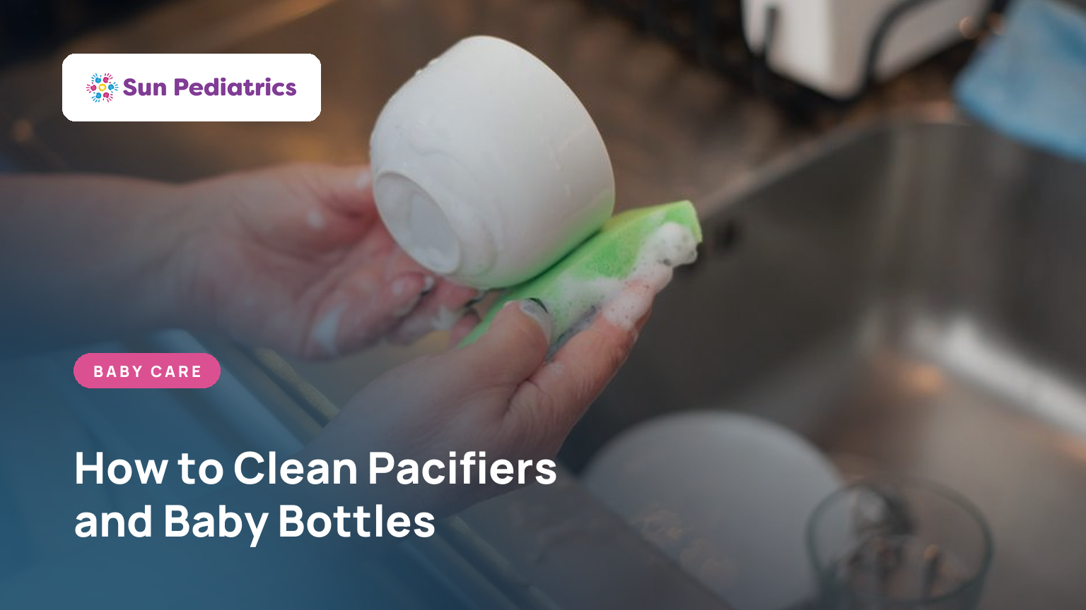 Parent washing a baby bottle with a brush at the kitchen sink, CDC steps for cleaning and sanitizing pacifiers and bottles